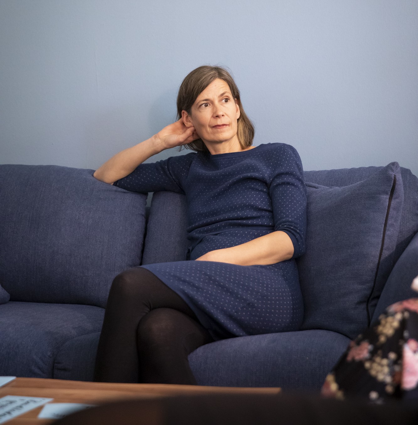 Christiane Temme sitzt nachdenklich auf einem blauen Sofa