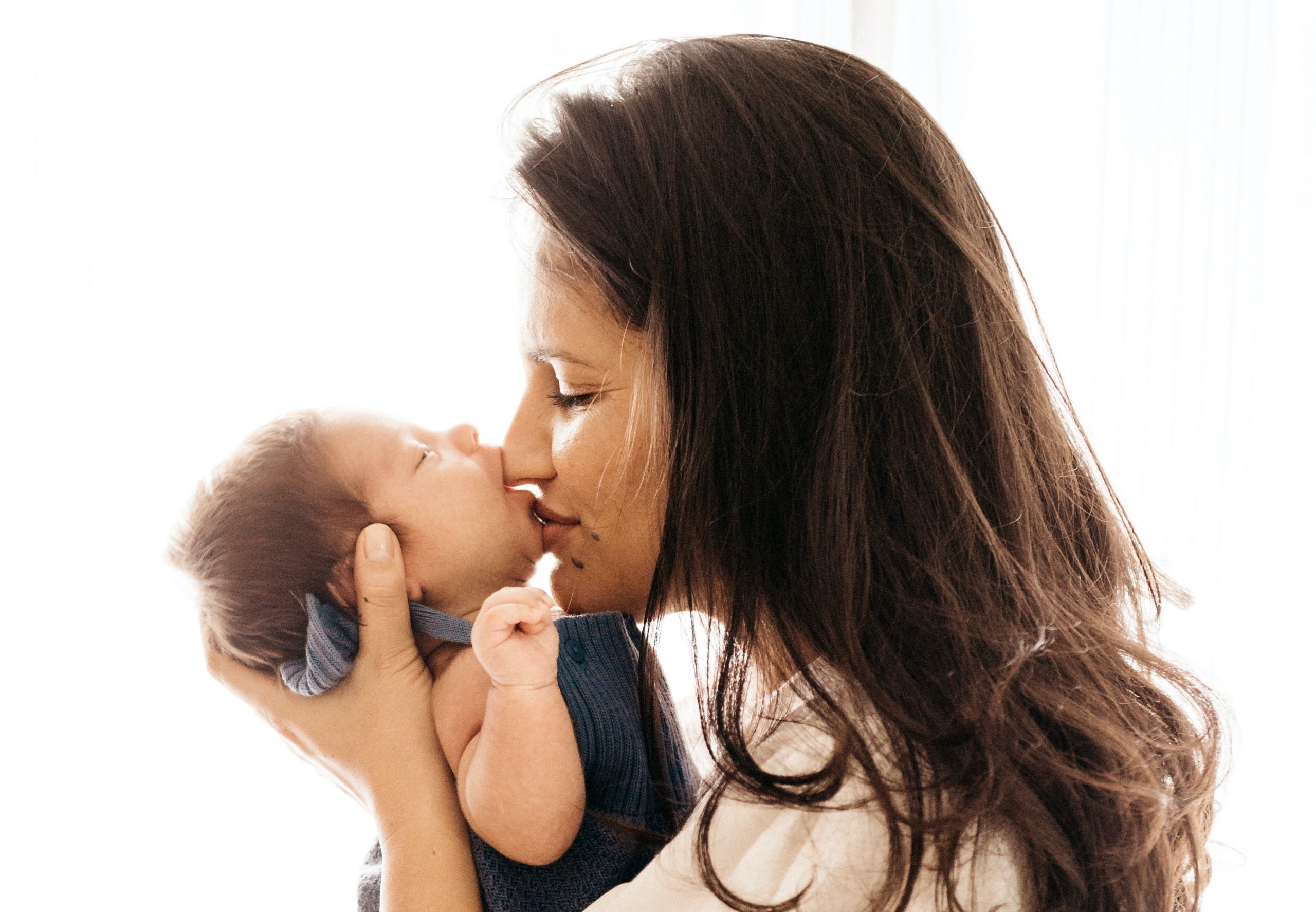 Eine Mutter küsst ihren neugeborenen Säugling